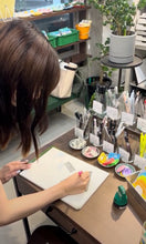 画像をギャラリービューアに読み込む, 文房具店の店内でカラーペンで試し書きをする女性