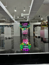 画像をギャラリービューアに読み込む, アパレルショップ店内に設置されたピンク・ホワイト・イエロー・グリーンのカラフルなネオンサインロゴ