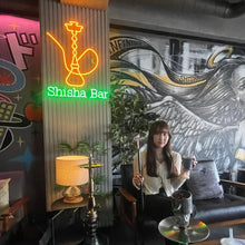 画像をギャラリービューアに読み込む, シーシャバー店内に設置されたオレンジとグリーンのシーシャ型ネオンサインロゴとシーシャを手に持つ女性