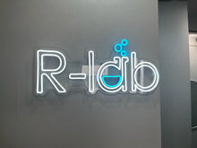 画像をギャラリービューアに読み込む, 美容室の店内壁に設置されたホワイトと水色のネオンサインロゴ
