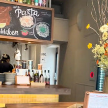 画像をギャラリービューアに読み込む, p-144-shitorabaの店内 客席から見えるキッチンに重ねられたお皿やお酒と上に設置されたおしゃれなメニューボード
